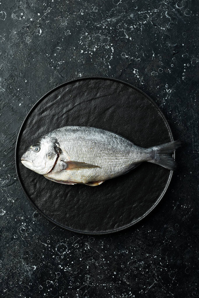 Dorado fish on a black stone plate. Seafood. Top view. On a black stone background. - Фото, изображение