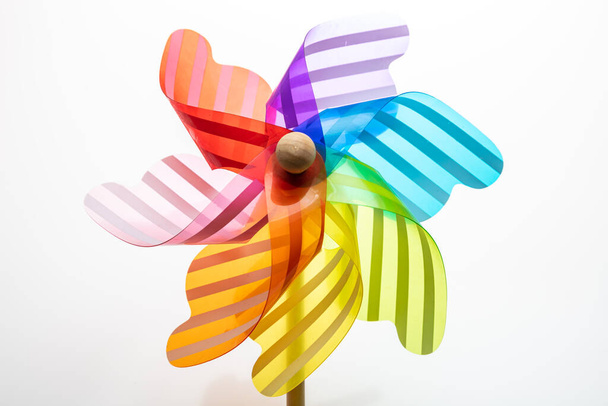 Windrad isoliert auf weißem Hintergrund. Windmühlenspielzeug in Regenbogenfarbe auf einem Holzstab - Foto, Bild