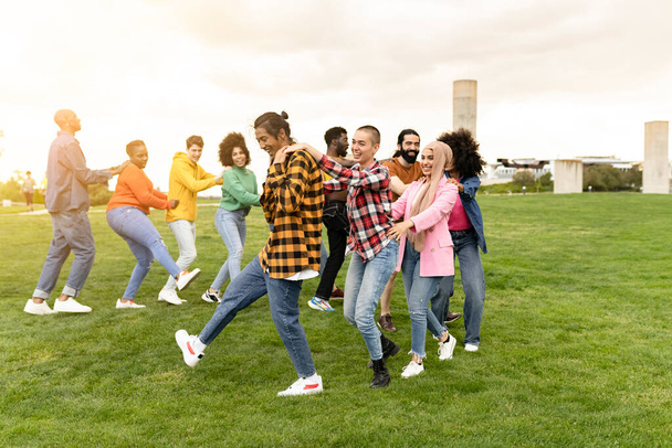 Wieloetniczna grupa przyjaciół bawiąca się razem tańcząc na świeżym powietrzu podczas wakacji - Zdjęcie, obraz