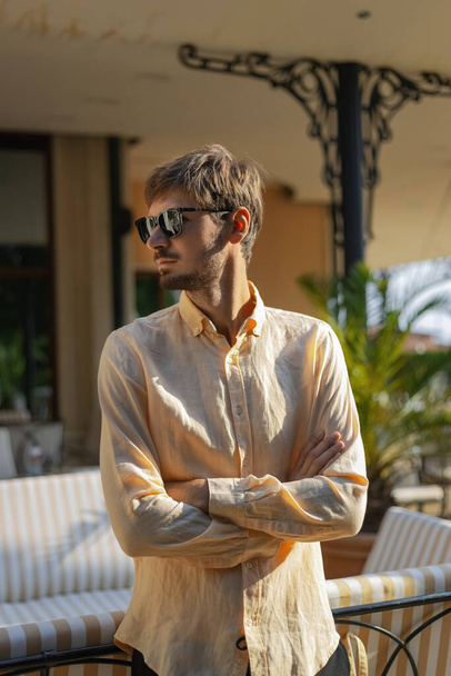 Ein europäisch aussehender Mann mit orangefarbenem Hemd und Sonnenbrille. Ein tropisches Land im heißen Sommer.  - Foto, Bild