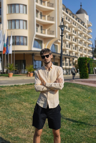 Um homem de aparência europeia com uma camisa laranja e óculos de sol. Um país tropical no verão quente.  - Foto, Imagem
