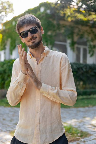 Un homme au look européen portant une chemise orange et des lunettes de soleil. Un pays tropical pendant l'été chaud.  - Photo, image