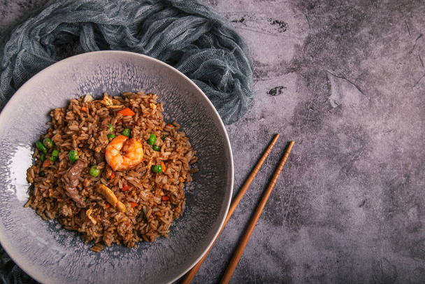 Typowe orientalne danie ryżowe wok serwowane na talerzu z rustykalnym tle i przestrzeń kopiowania - Zdjęcie, obraz