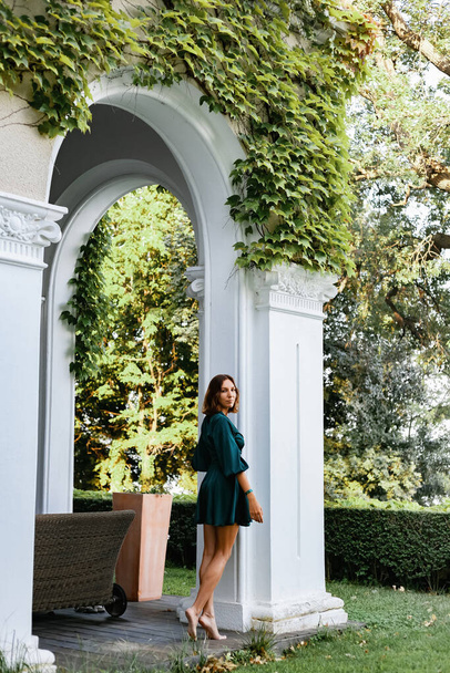 Una ragazza sorridente e sofisticata in un abito leggero turchese passeggia in un parco verde ben curato. E 'un'estate calda in un paese tropicale.  - Foto, immagini