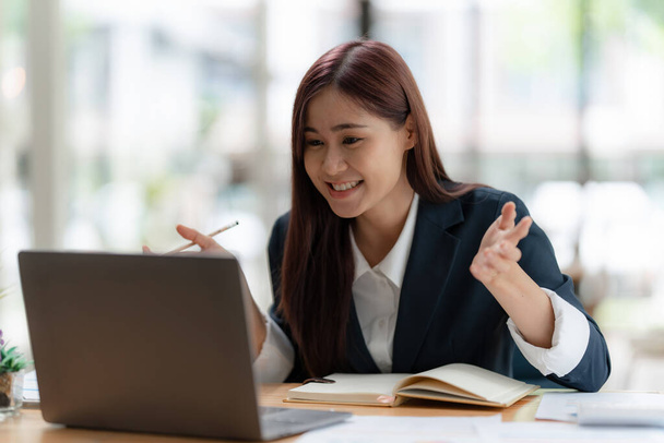 デジタルオンライン会議の概念。アジアのビジネス女性はオフィスのラップトップコンピュータで彼女のパートナーと会議を持っています - 写真・画像