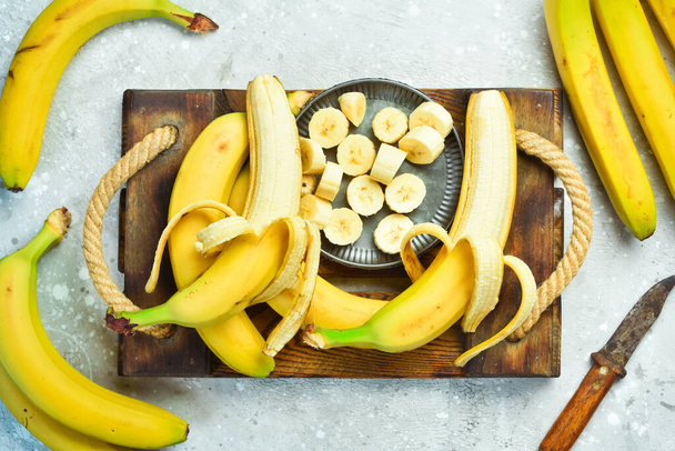 Fresh bananas sliced in a bowl. Tropical bananas on a gray concrete background. Top view. - Foto, Bild