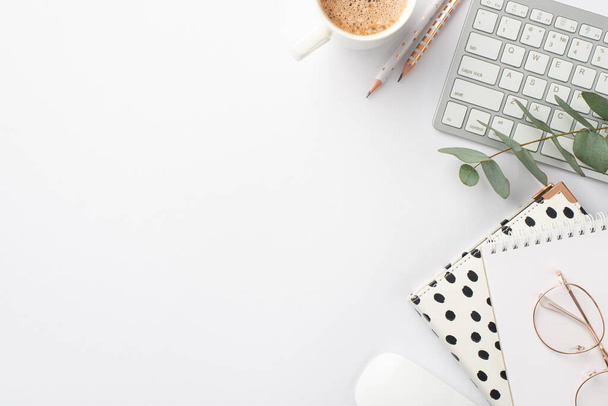 Geschäftskonzept. Foto von der Arbeitsfläche Tastatur Computermaus stilvolle Notizblöcke Bleistifte Tasse Kaffeegläser und Eukalyptuszweig auf isoliertem weißem Hintergrund mit leerem Raum - Foto, Bild