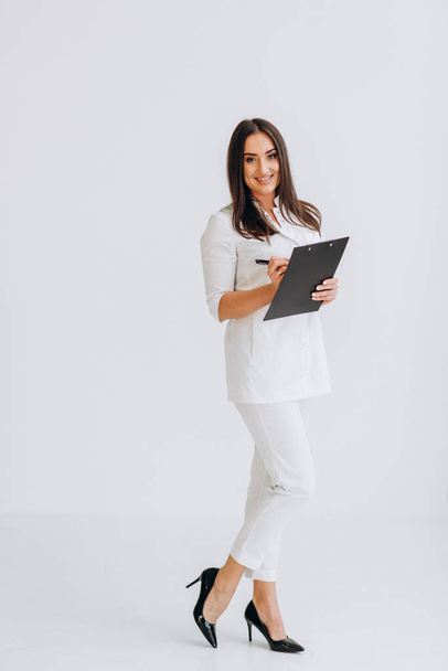 Dentist in white coat and glasses stands holding folder - Photo, Image