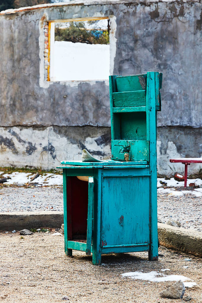 Tamamlanmamış bir evin arka planında terk edilmiş klasik bir sokak tuvaleti. - Fotoğraf, Görsel
