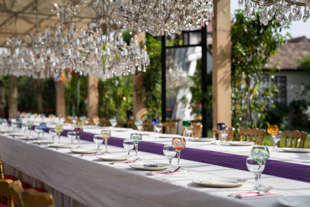 Vidros e taças de cristal e vidro, pratos brancos, talheres para o ambiente de mesa festiva para casamento luxuoso ou festa de aniversário. Foco suave.  - Foto, Imagem