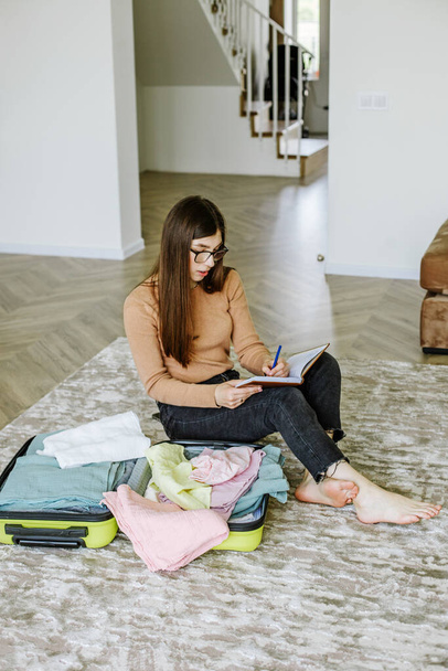 Travel fashion. Holiday beach. Beach bag. Happy young woman packing travel suitcase at home. Vacation preparation. Tourist trip. - Foto, imagen