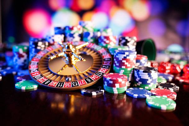 Casino theme.  Roulette wheel and poker chips on  colorful bokeh background. - 写真・画像