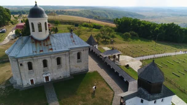 The groom holds the bride in his arms and spins with her. Against the background of the ancient Church of the Assumption of the Blessed Virgin, Krylos. - Footage, Video