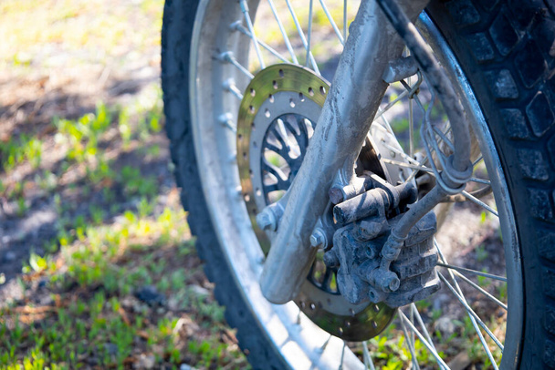 Detailní záběr předního kola motocyklu zaparkovaného na trávě. Kvalitní fotografie - Fotografie, Obrázek