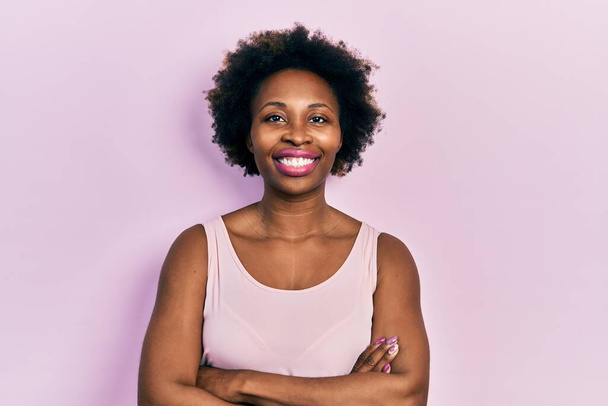 Young african american woman wearing casual sleeveless t shirt happy face smiling with crossed arms looking at the camera. positive person.  - Photo, Image