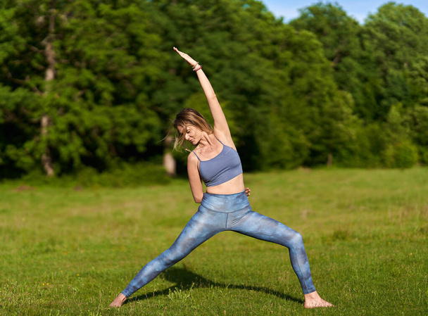 Young woman practicing yoga and meditation in a forest with centennial oak trees - Foto, Imagen