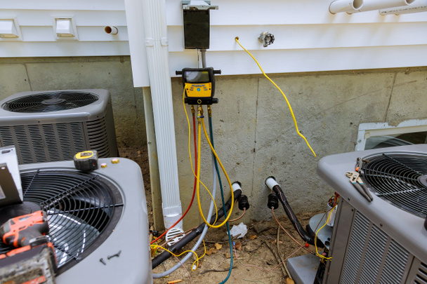 Técnico de reparación de la unidad de aire acondicionado al aire libre con multímetro medidor de refrigeración líquida - Foto, Imagen