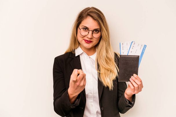 Young business caucasian woman holding a passport isolated on white background pointing with finger at you as if inviting come closer. - 写真・画像