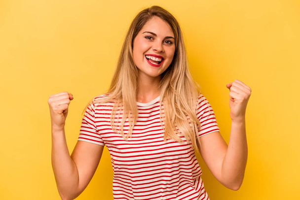 Young caucasian woman isolated on yellow background cheering carefree and excited. Victory concept. - Photo, Image