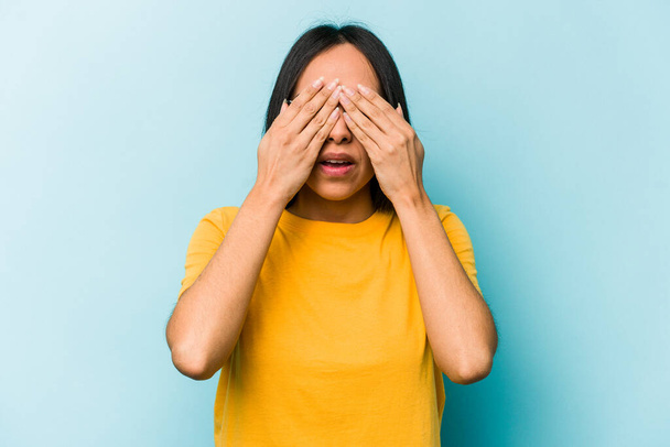 Young hispanic woman isolated on blue background afraid covering eyes with hands. - Photo, Image