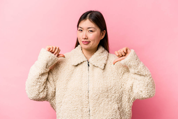 Young Chinese woman isolated on pink background showing thumb down, disappointment concept. - Foto, Imagem