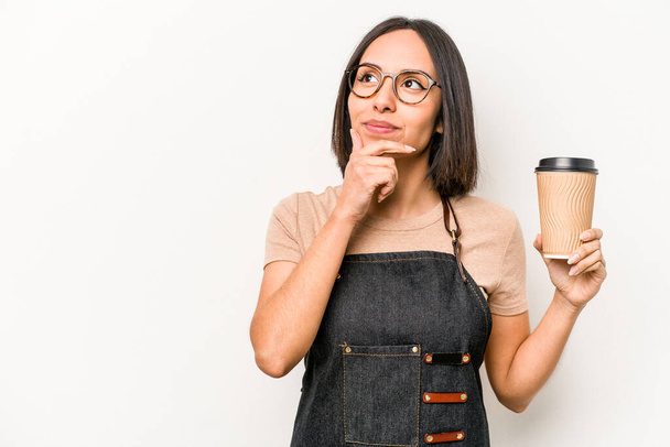 jovem caucasiano garçonete mulher segurando tirar café isolado no fundo branco olhando para os lados com expressão duvidosa e cética. - Foto, Imagem