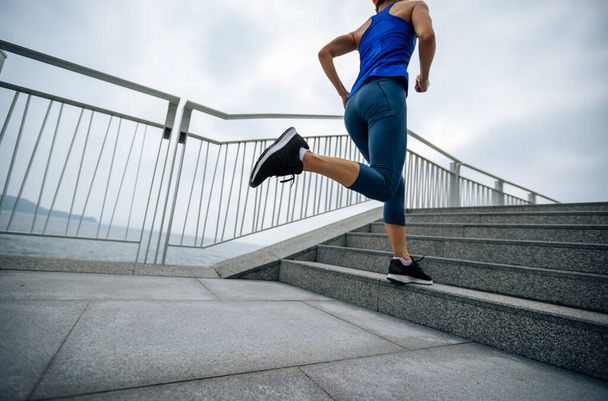 Healthy lifestyle fitness sports woman runner running up stairs on seaside trail - 写真・画像