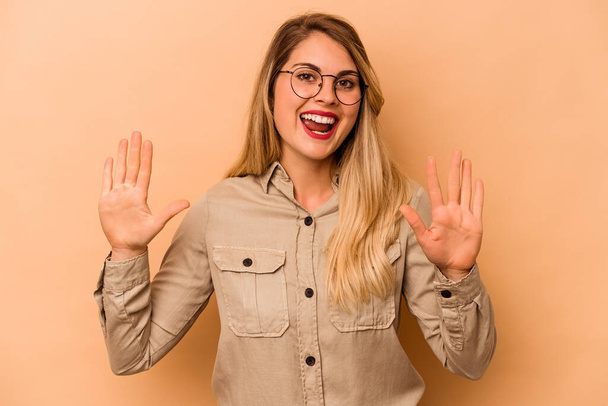 Young caucasian woman isolated on beige background receiving a pleasant surprise, excited and raising hands. - Foto, afbeelding