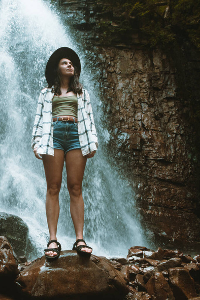 kobieta w brązowym kapeluszu korzystających widok na wodospad turystyka koncepcja podróży - Zdjęcie, obraz