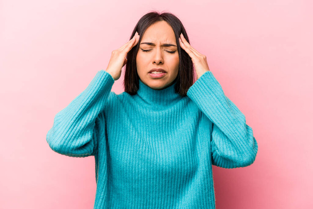 Junge hispanische Frau isoliert auf rosa Hintergrund berührt Schläfen und hat Kopfschmerzen. - Foto, Bild