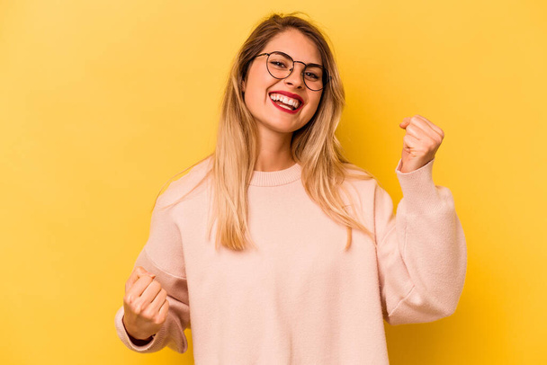 Young caucasian woman isolated on yellow background cheering carefree and excited. Victory concept. - Photo, Image