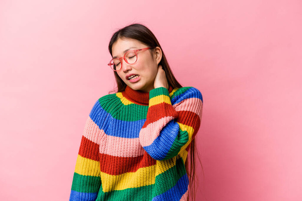 Giovane donna cinese isolata su sfondo rosa che soffre di dolore al collo a causa dello stile di vita sedentario. - Foto, immagini