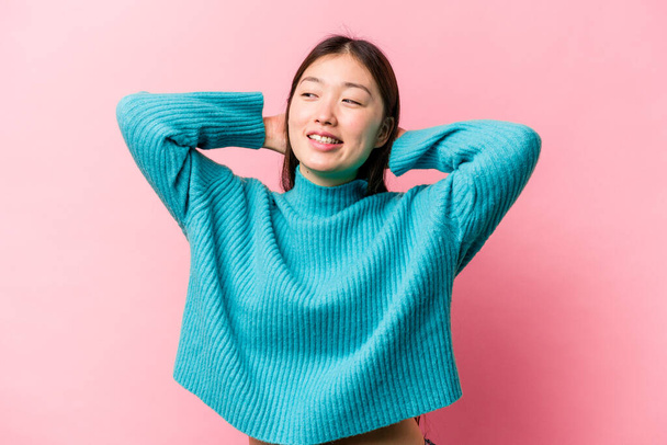 Young Chinese woman isolated on pink background feeling confident, with hands behind the head. - Photo, Image