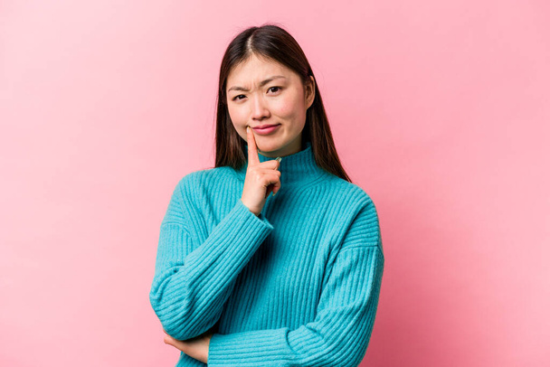 Joven mujer china aislada sobre fondo rosa infeliz mirando en cámara con expresión sarcástica. - Foto, imagen