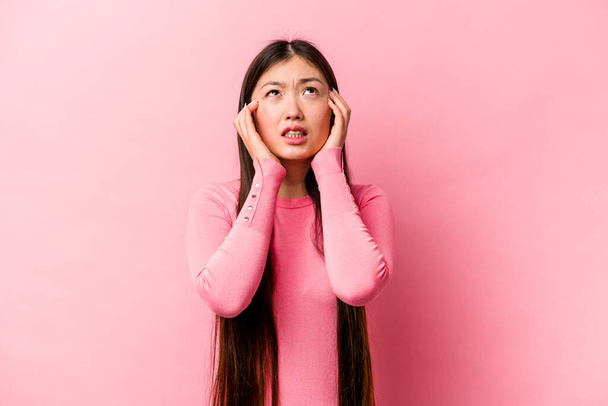 Νεαρή Κινέζα απομονωμένη σε ροζ φόντο κλαψουρίζει και κλαίει απαρηγόρητα. - Φωτογραφία, εικόνα