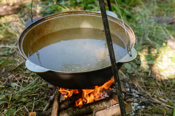 Caldero en el fuego. Cocinar comida en una fogata en un campamento salvaje en un día de verano. Concepto de descanso - Foto, imagen