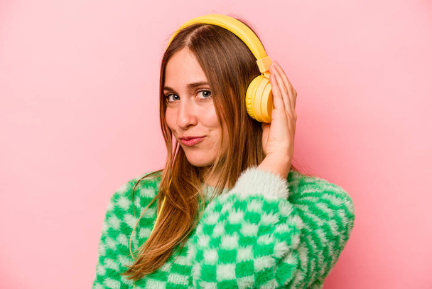 Jeune femme caucasienne écoutant de la musique isolée sur fond rose - Photo, image