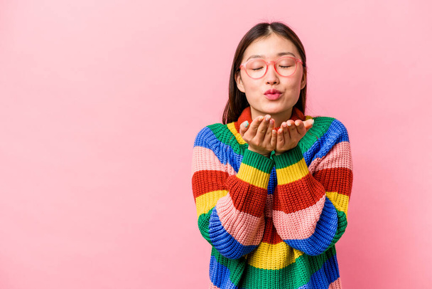 Joven mujer china aislada sobre fondo rosa plegable labios y la celebración de las palmas para enviar beso de aire. - Foto, Imagen