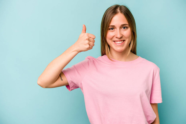 Young caucasian woman isolated on blue background smiling and raising thumb up - Foto, Bild