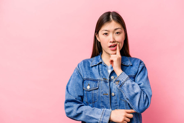 Joven mujer china aislada sobre fondo rosa mirando de lado con expresión dudosa y escéptica. - Foto, imagen