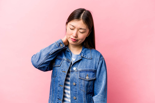Jonge Chinese vrouw geïsoleerd op roze achtergrond met een nek pijn als gevolg van stress, masseren en aanraken van het met de hand. - Foto, afbeelding