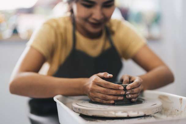 ポッターホイールで働く女性。土鍋からカップを作る職人。陶芸家ホイールの手作りモデリングのワークショップ - 写真・画像