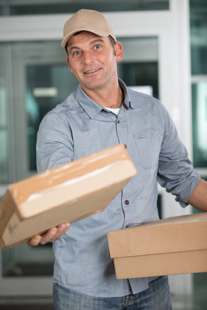 deliveryman in uniform holds parcels - Fotó, kép