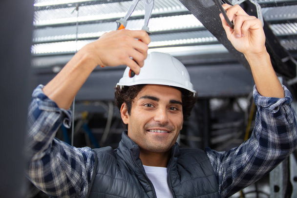 young builder replacing ceiling panel - Фото, изображение