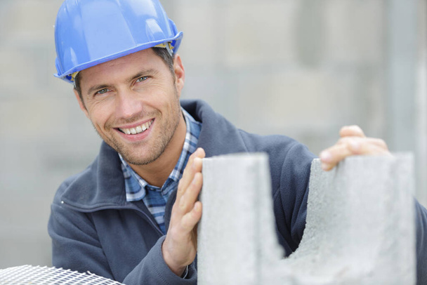 happy male builder holding a cement block - Foto, afbeelding