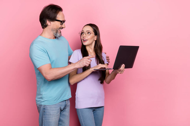 Photo de deux partenaires positifs embrasser parler communiquer point netbook isolé sur fond de couleur rose. - Photo, image