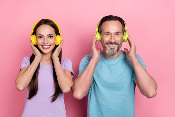 Photo of two cheerful carefree people hands touch headphones look camera isolated on pink color background. - Foto, afbeelding