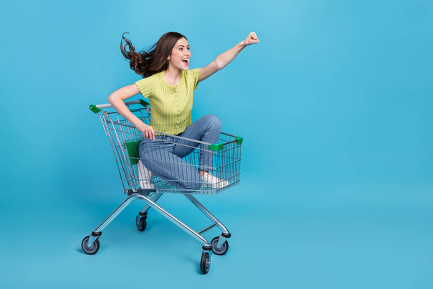 Full length photo of cool millennial brunette lady go in trolley yell wear t-shirt jeans footwear isolated on blue background. - Foto, Imagen