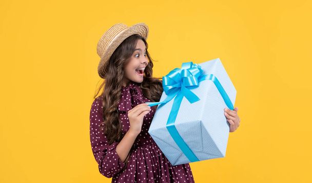surprised teen girl with present box on yellow background. - Фото, зображення