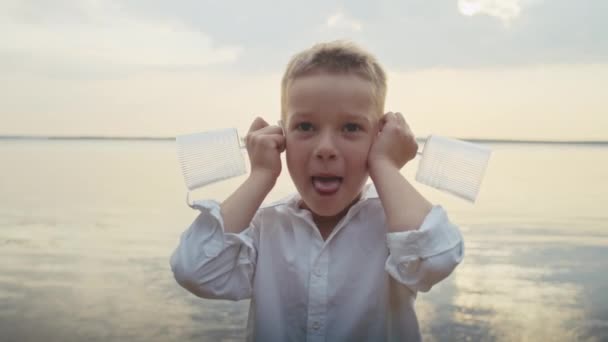 een vrolijk kind geniet in een vijver, zet een bril op zijn oren en grimmig - Video